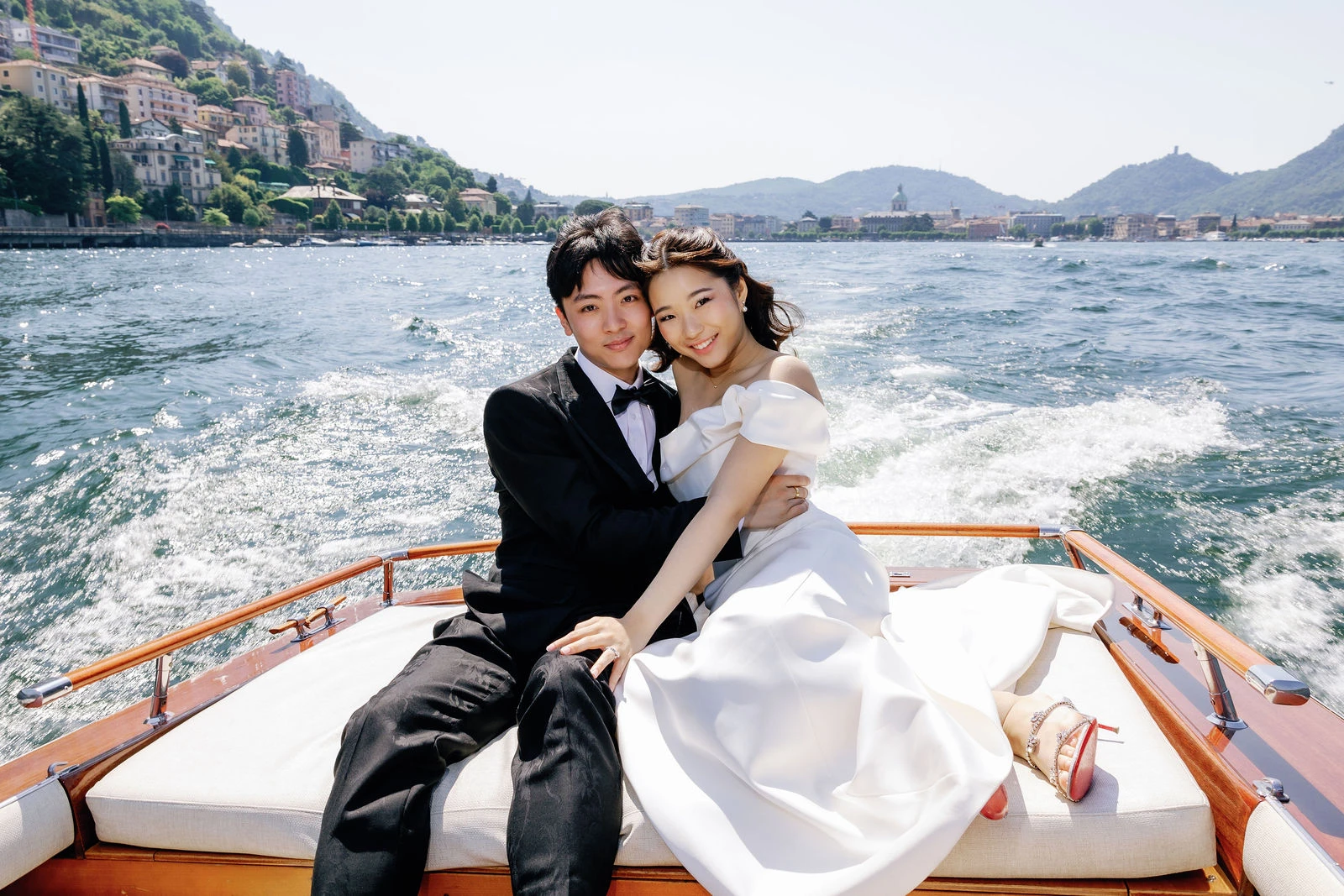 Couple on a wooden boat speeding across Lake Como