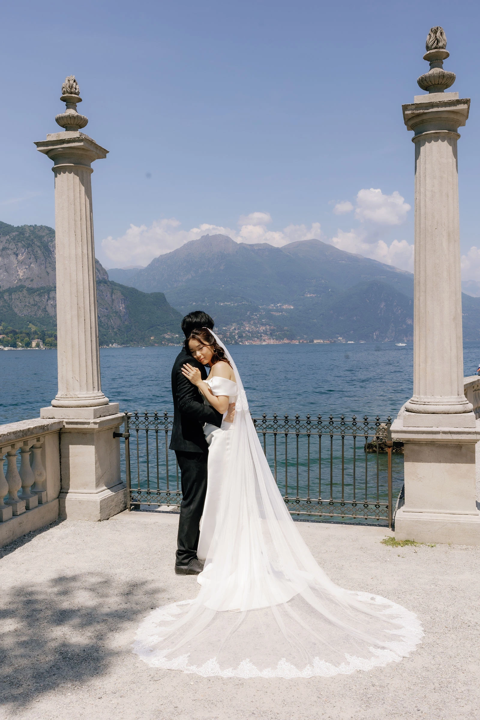 Bride and groom between stone columns above Lake Como