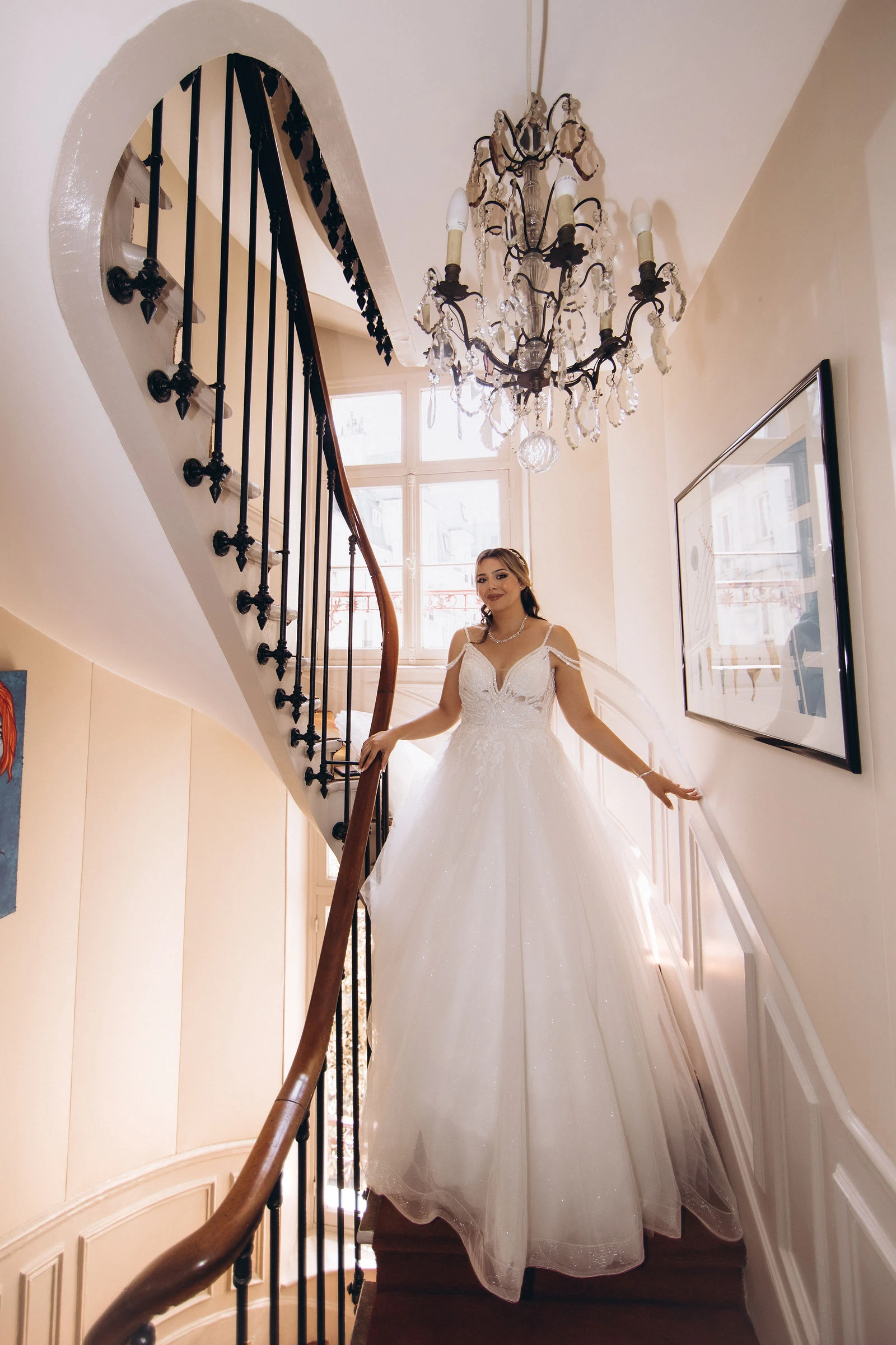 Bride on a spiral staircase under a chandelier in a Paris hotel