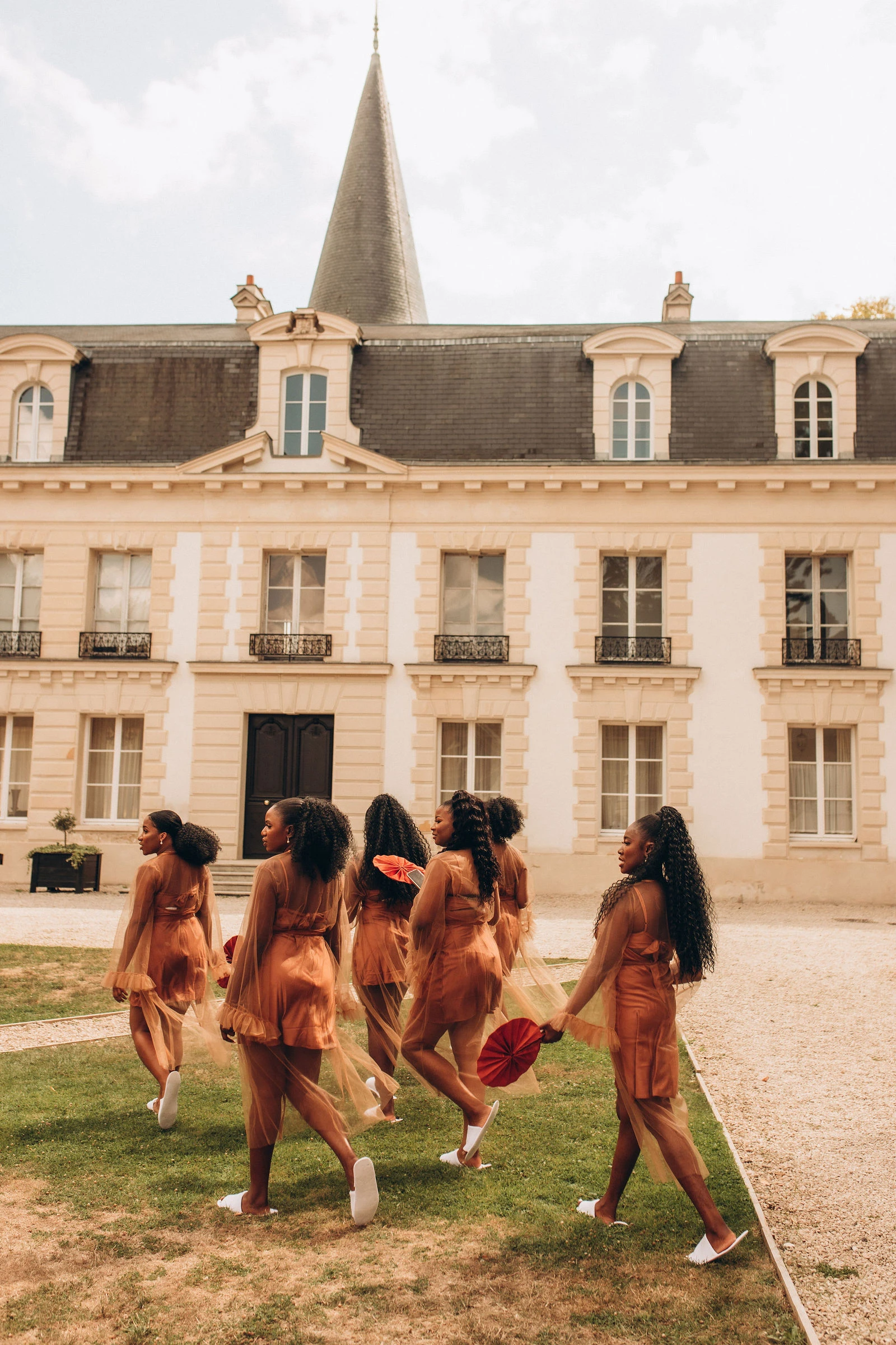 Bridesmaids in orange walking past the château