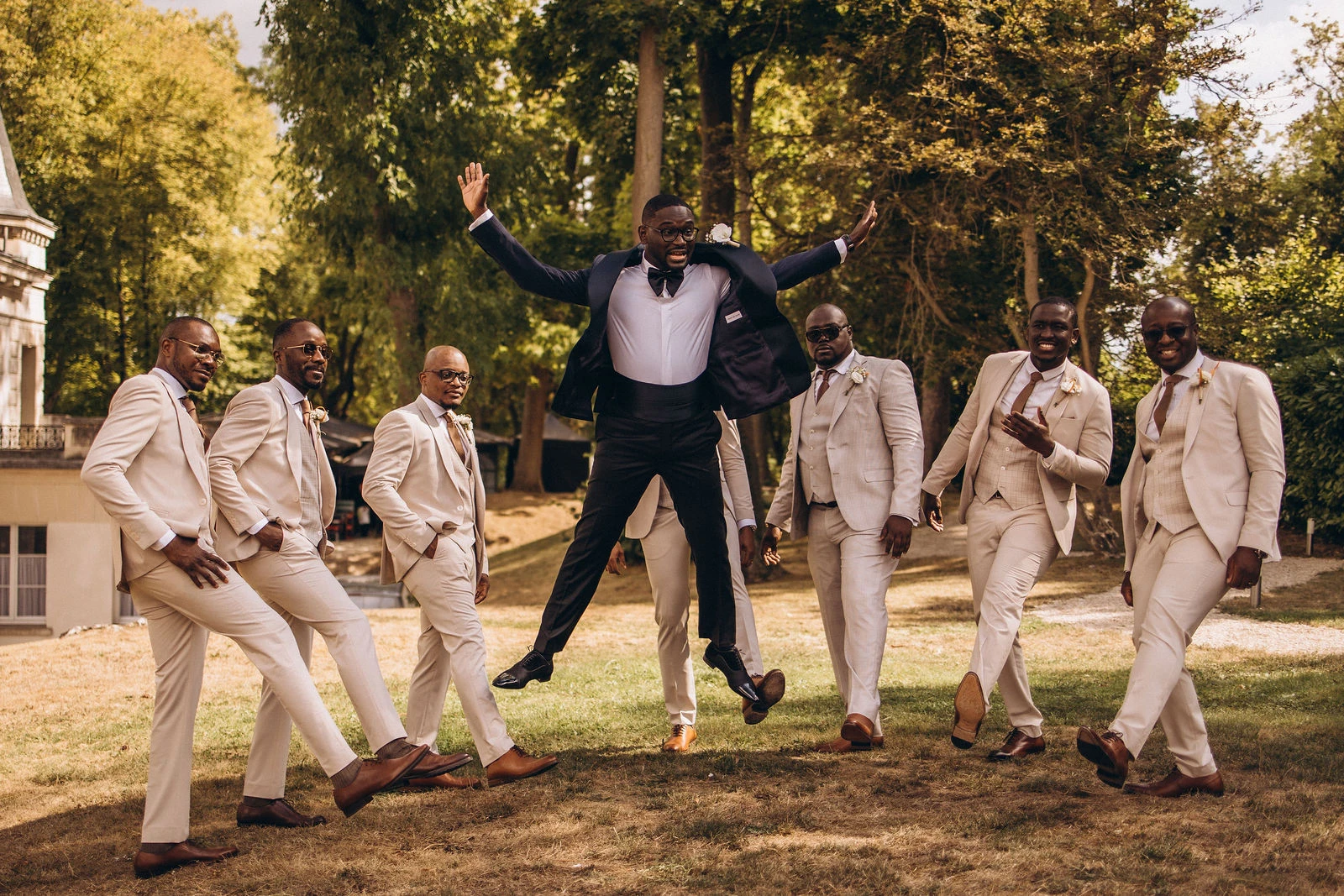 Groomsmen jumping on the château lawn