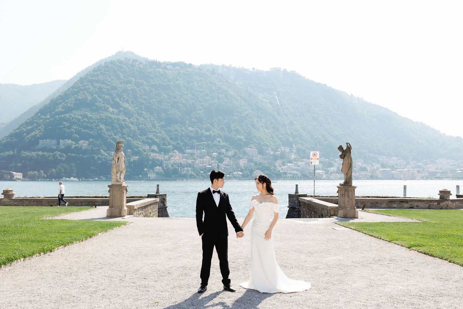 Bride and groom on the lakefront in Como, mountains behind