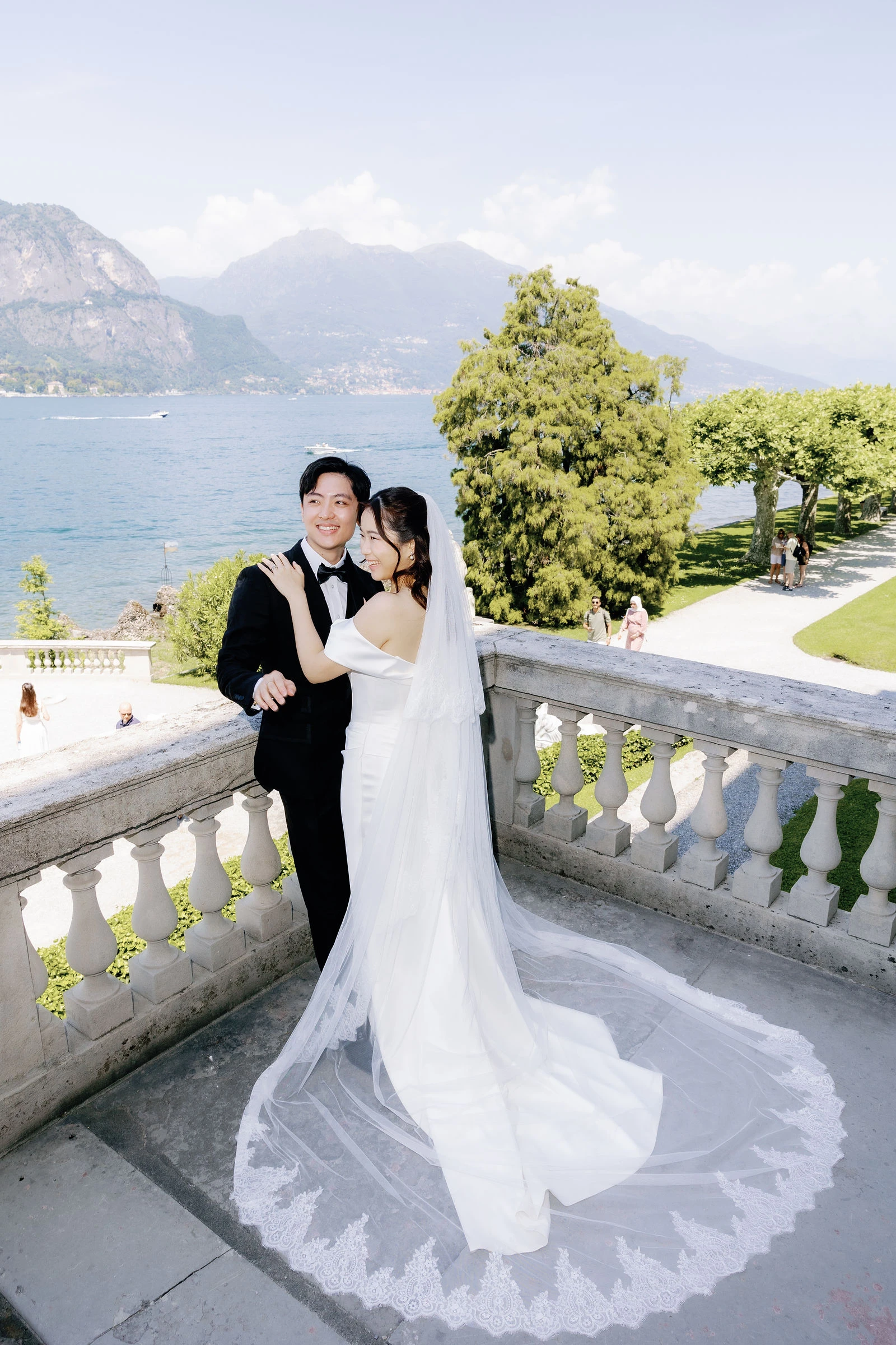 Bride and groom on a balustrade above Lake Como
