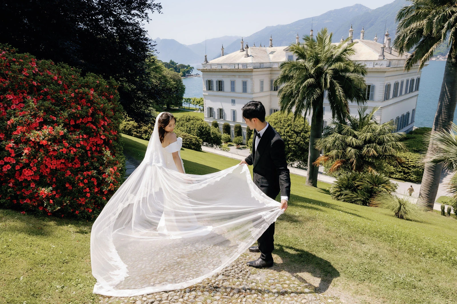 Groom lifting the long veil in the Villa Melzi gardens