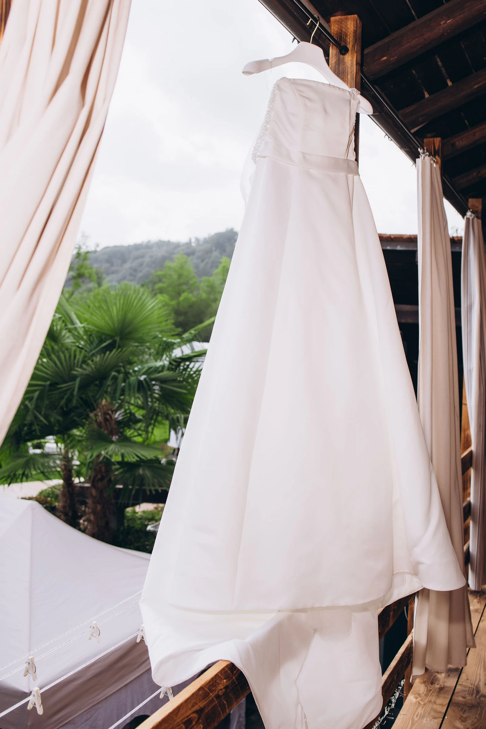 Wedding dress hanging on a wooden balcony at an Italian countryside villa