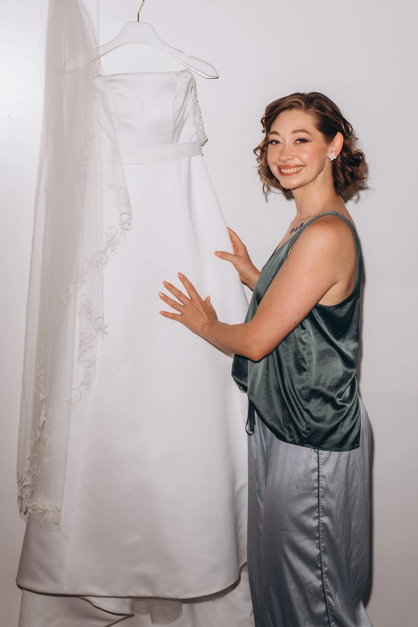 Bride smiling beside her dress on its hanger