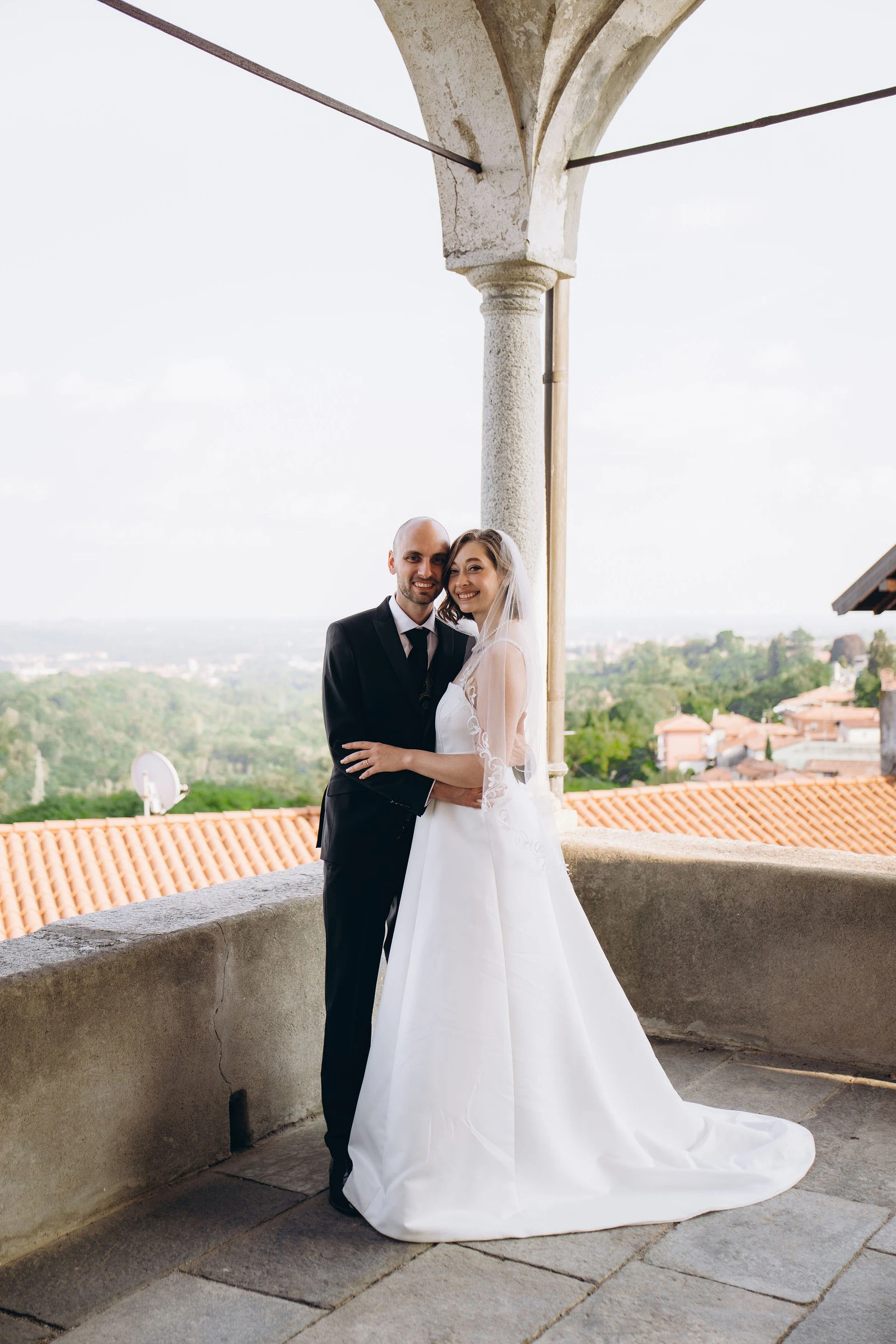 Newlyweds under the arches of a hilltop portico