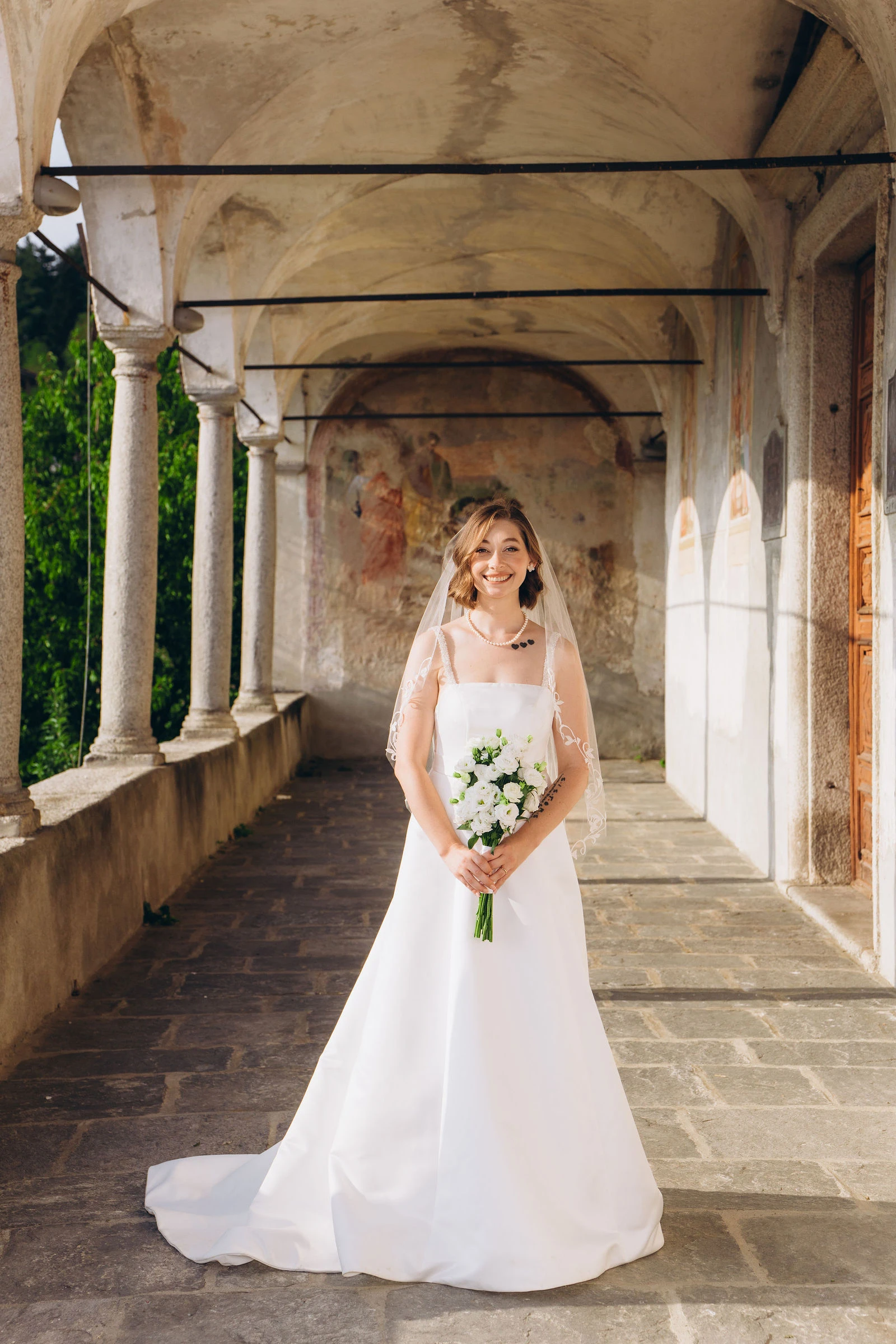 Bride with her bouquet in a columned gallery