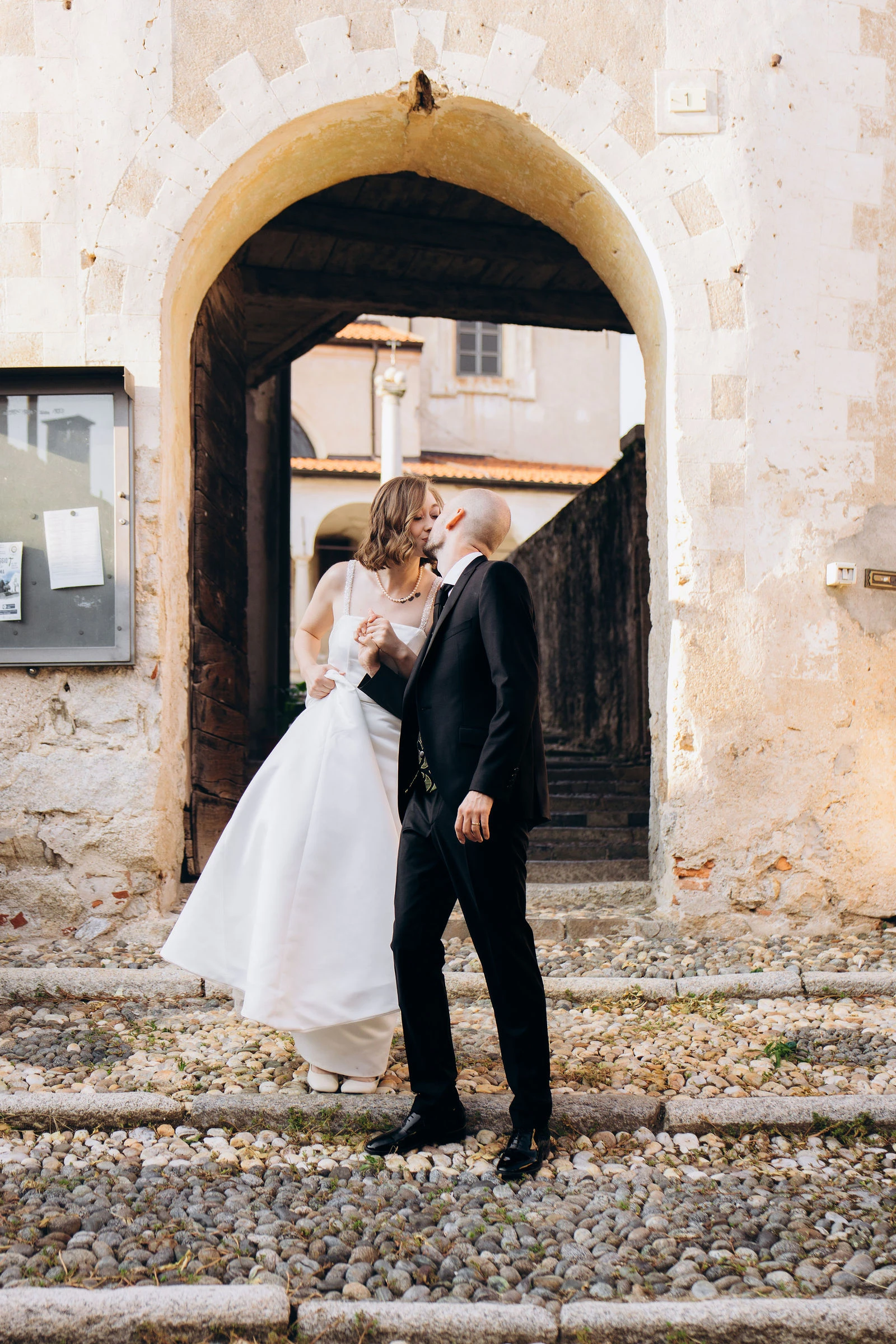 Newlyweds beneath an old stone archway