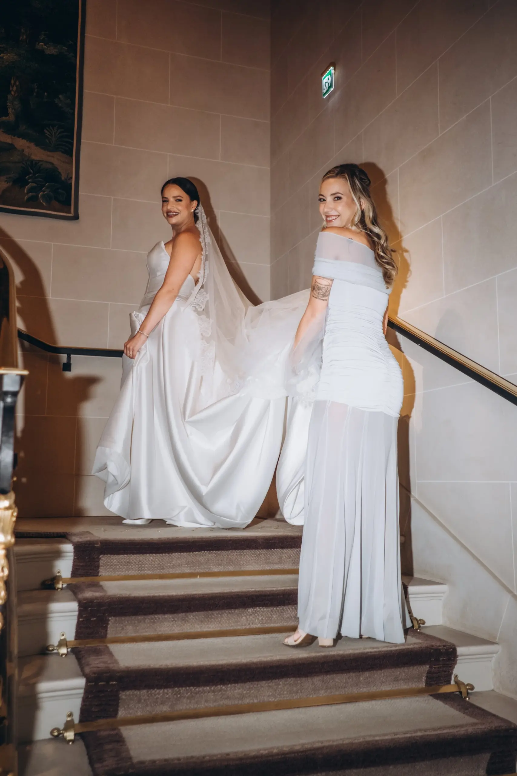 Bride and her sister on the stairs, holding the train