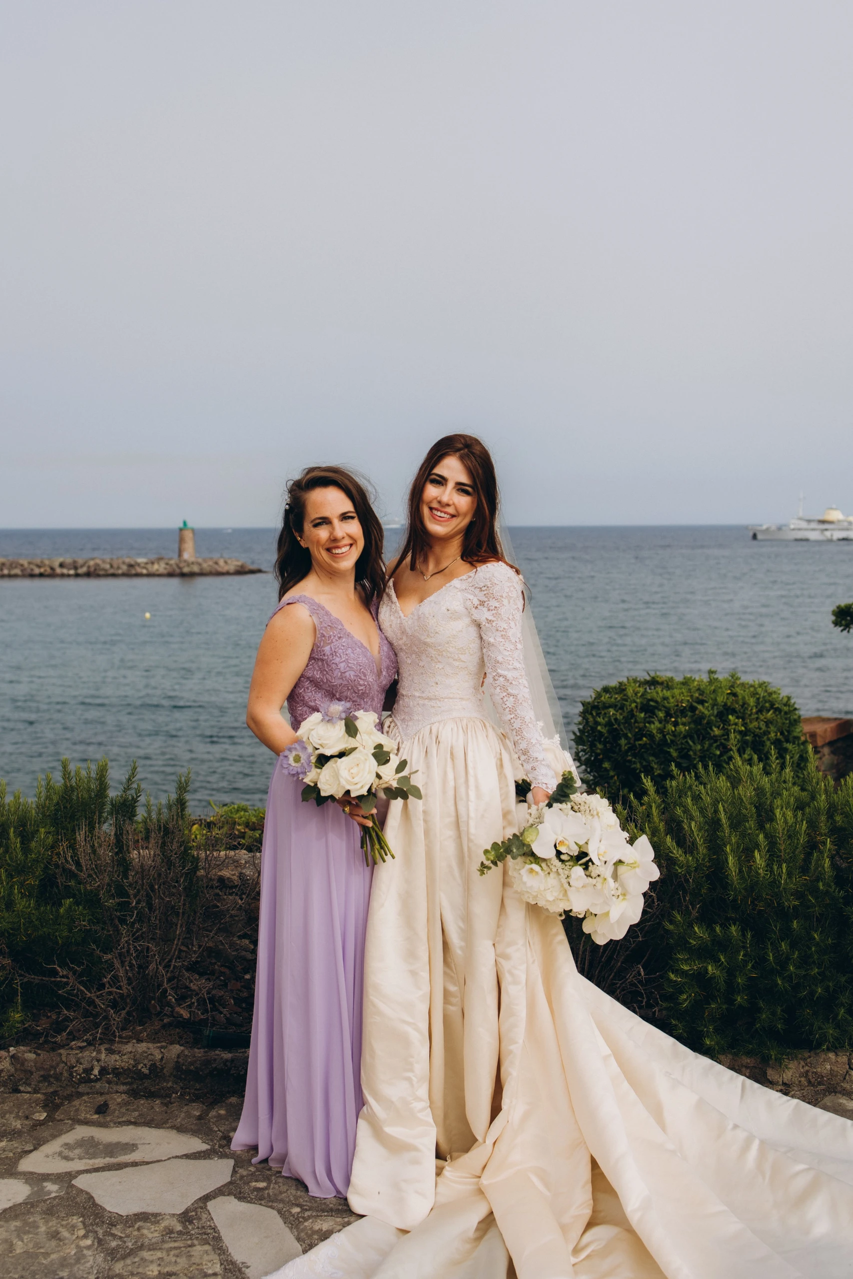 Bride with her sister in lilac by the sea