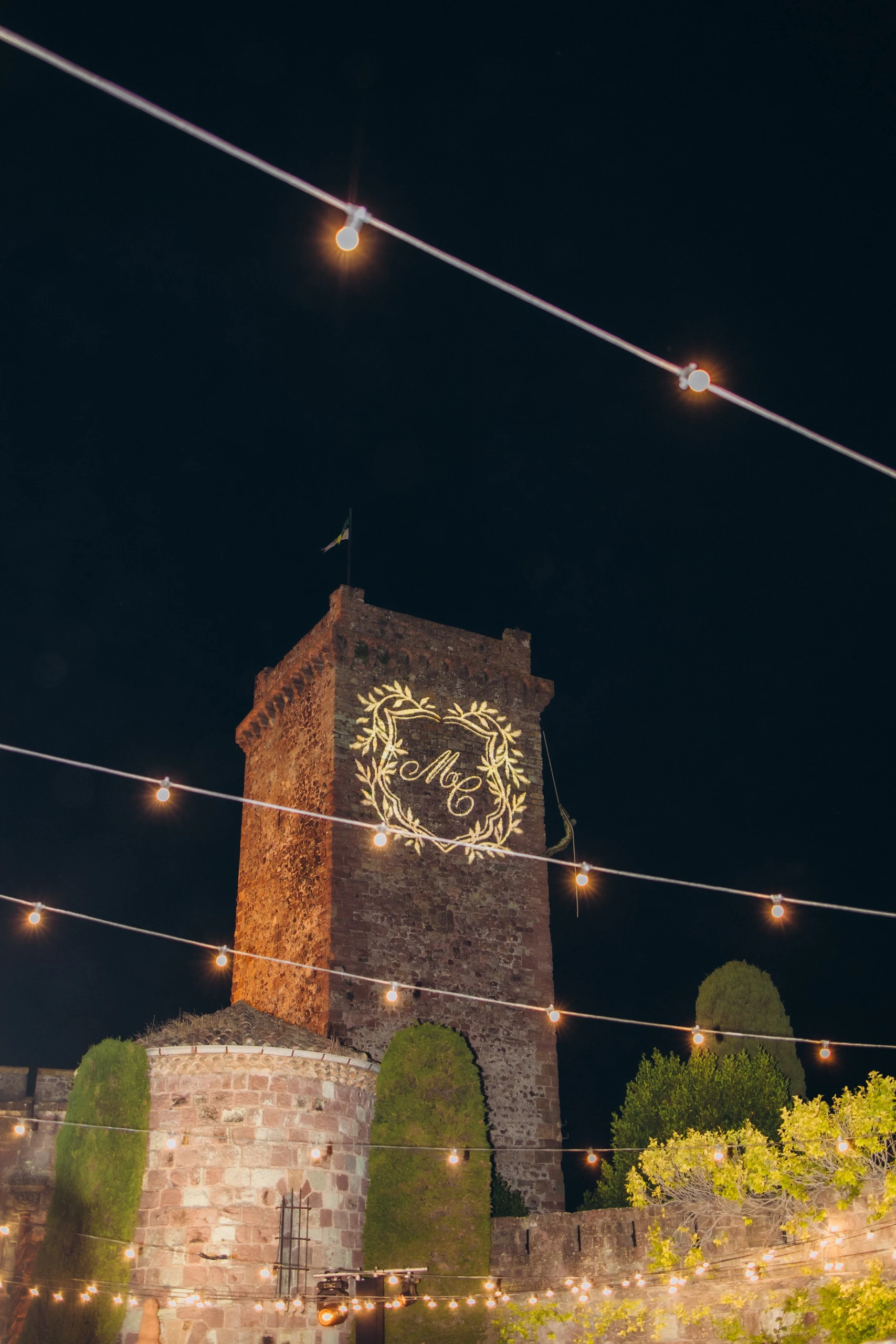 The tower of Château de La Napoule at night under string lights