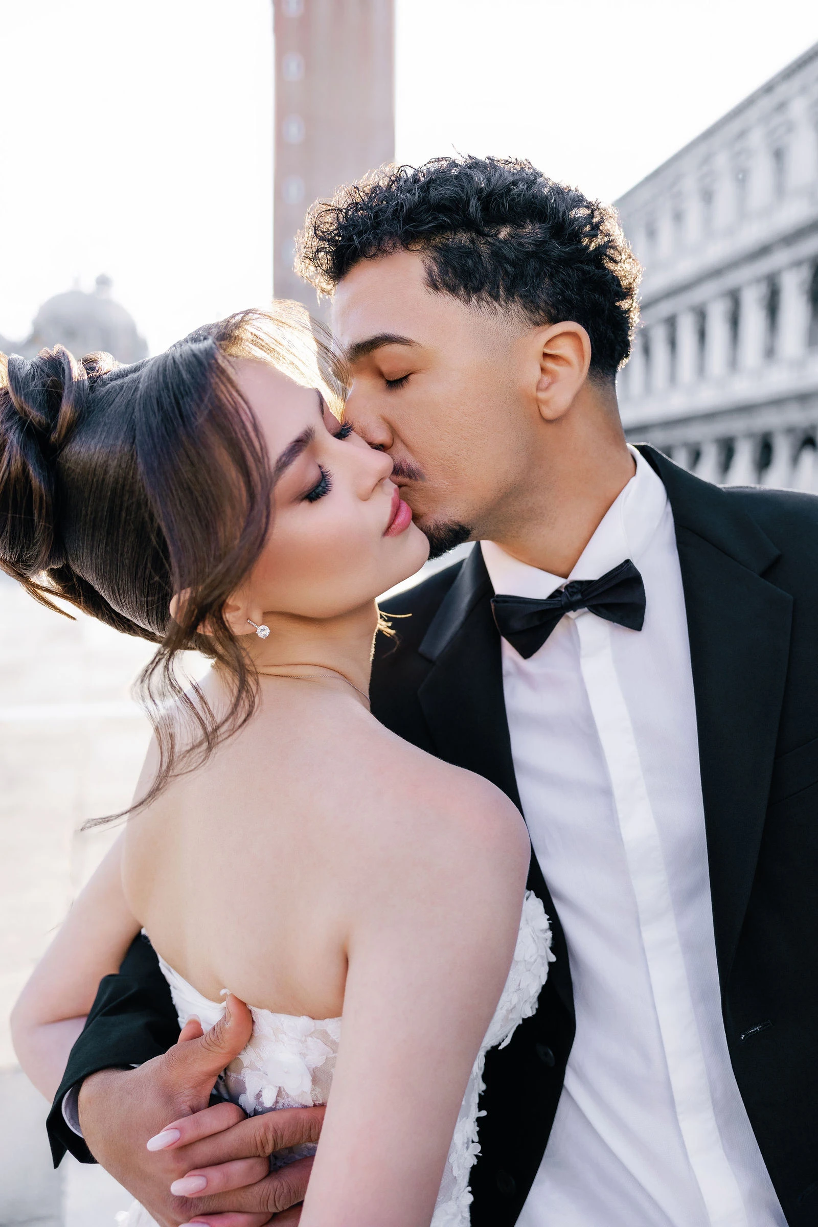 Groom kissing the bride by the campanile, Venice